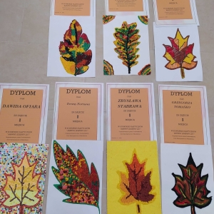 Dyplomy za zajęcie I miejsca oraz prace uczestników przedstawiające jesienny liść 